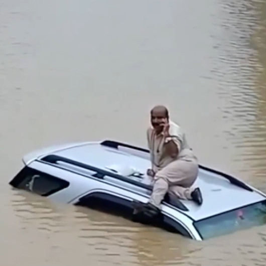 Hindistan’da sele kapılan sürücü aracının üzerinde kurtarılmayı bekledi